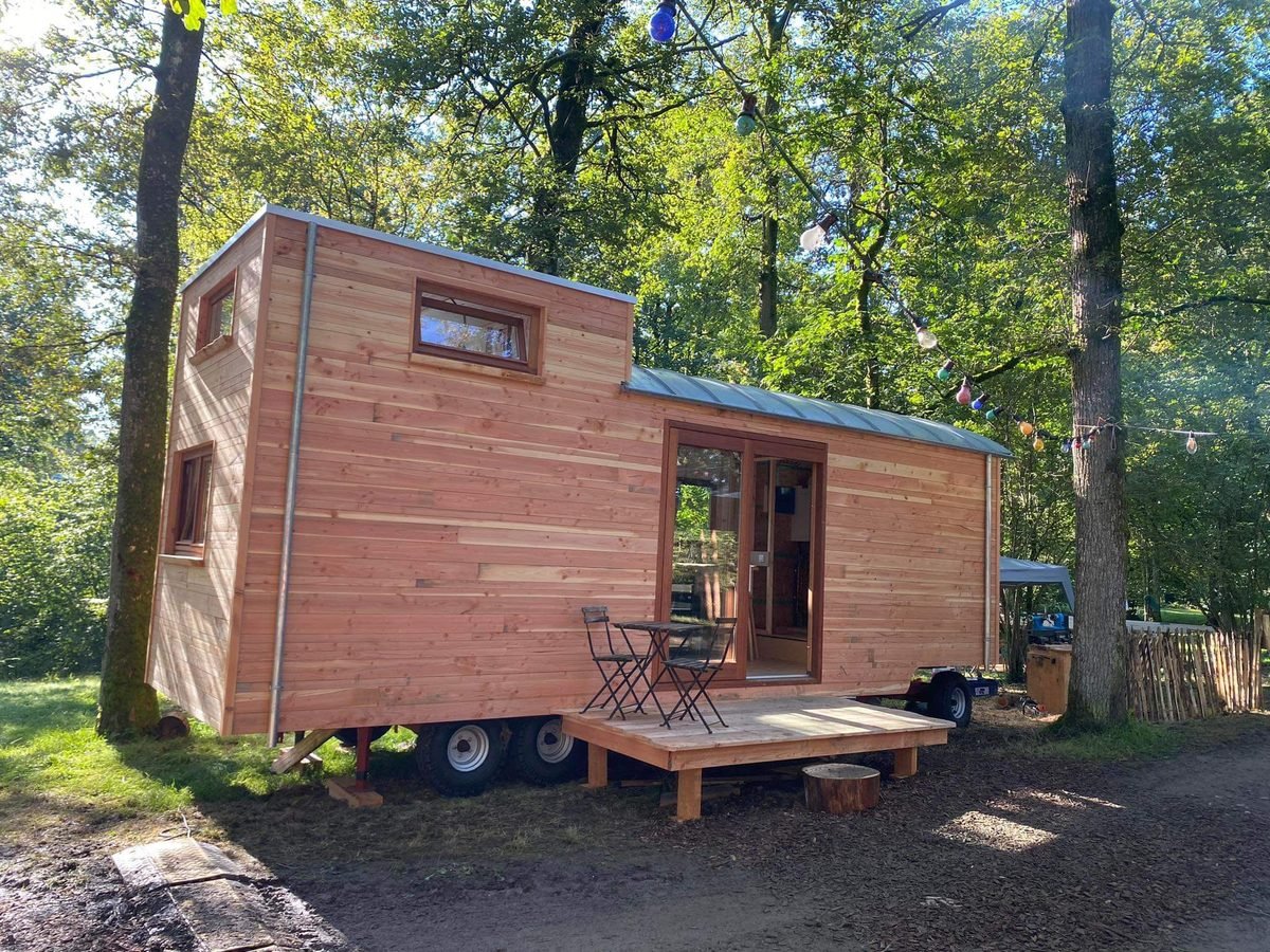 Roulotte artisanale en bois installée au bord des arbres